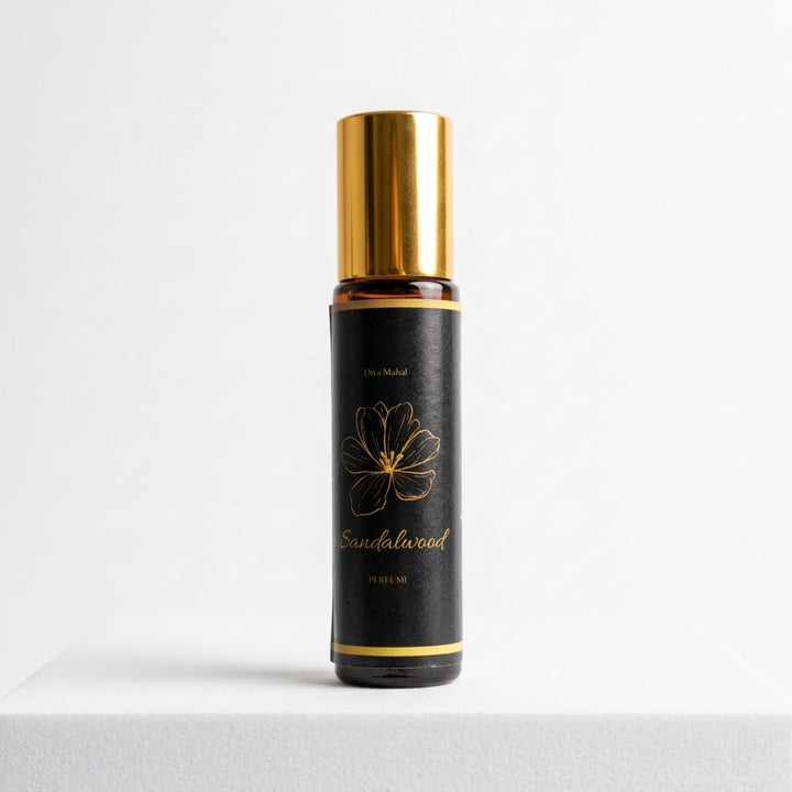  10ml roll-on bottle of Sandalwood Perfume by Diva Nihal, featuring a black label with a gold floral design and gold lettering, topped with a shiny gold cap, set against a clean white background.