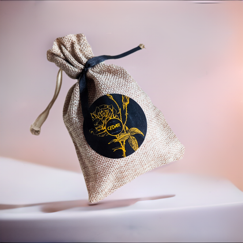 A small burlap sack with a black label featuring a gold floral design, tied with a string.