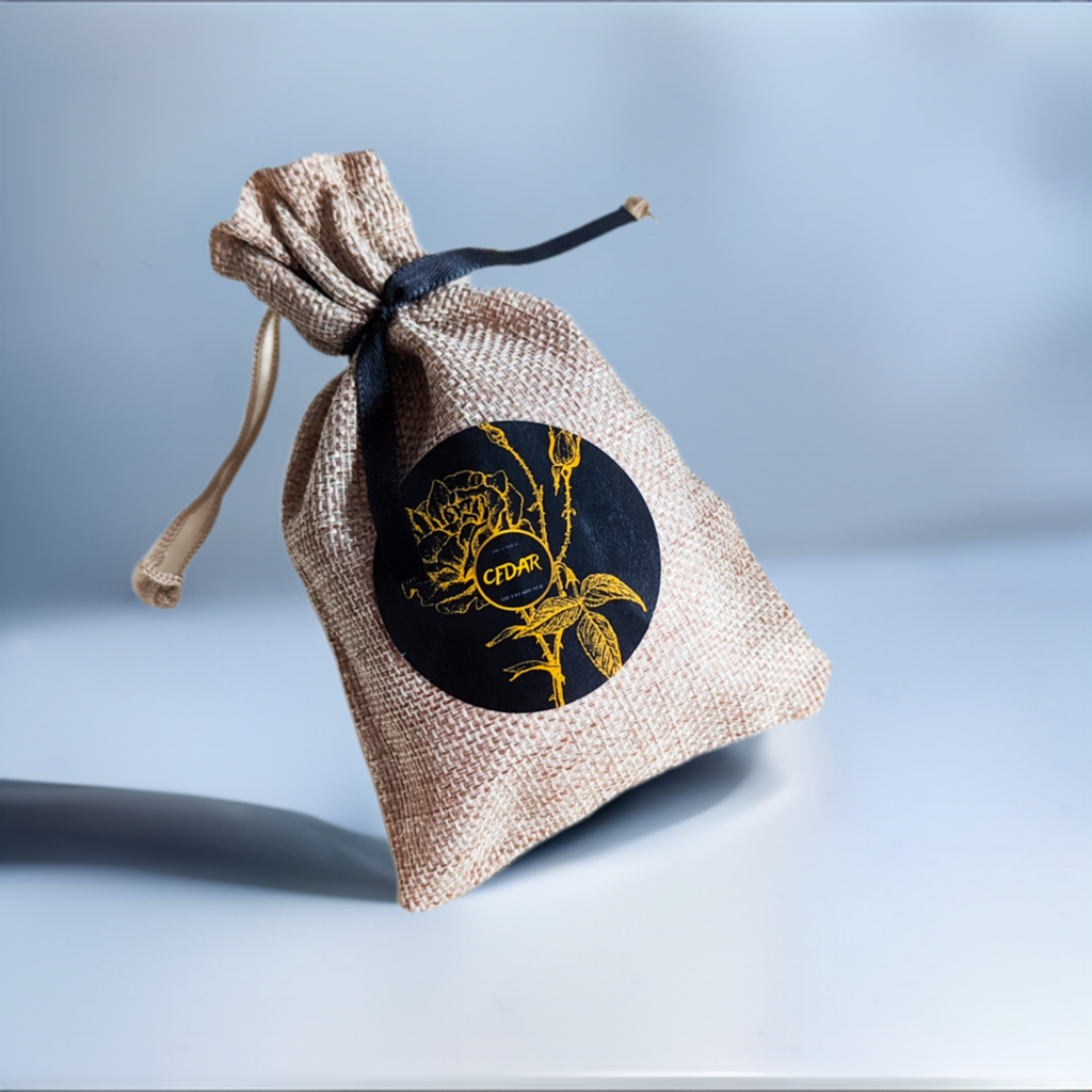 A small burlap sack with a black label featuring a gold floral design, tied with a black ribbon.