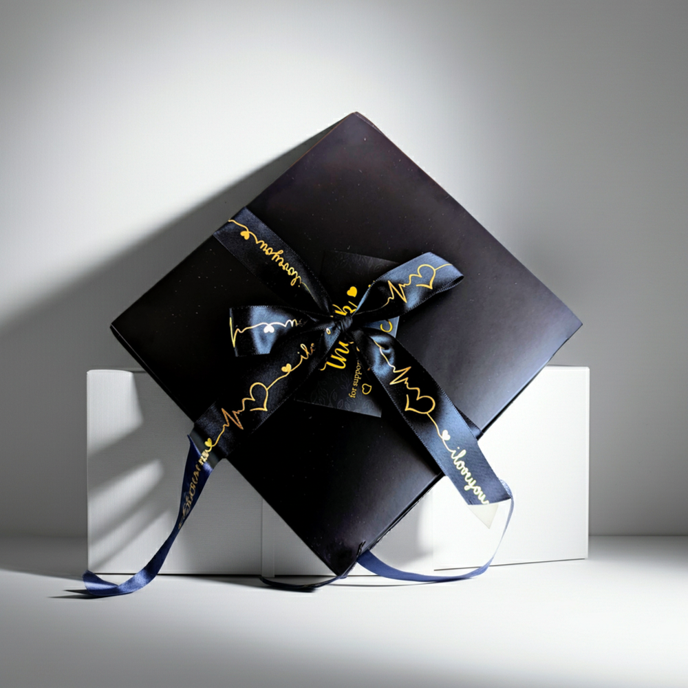 Black gift box with a decorative ribbon on a white surface