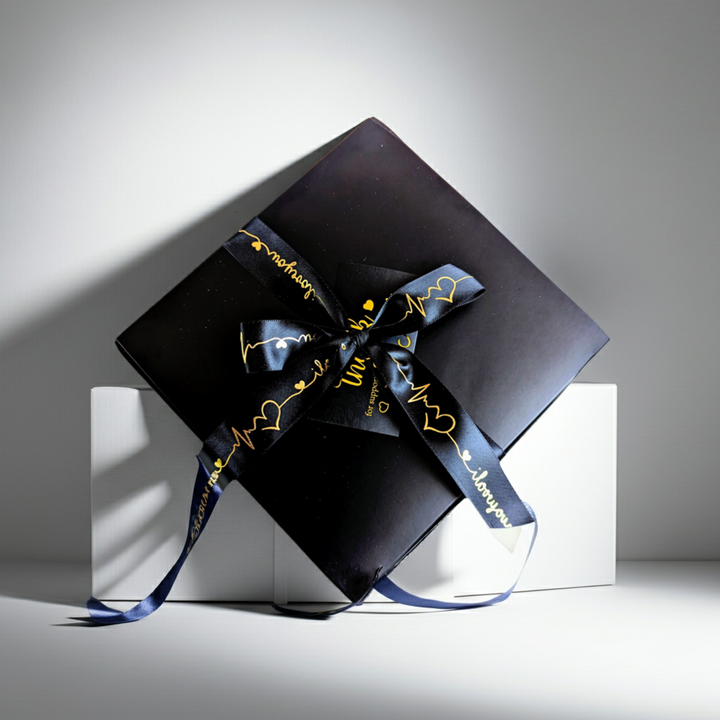 Black gift box with a decorative ribbon on a white surface