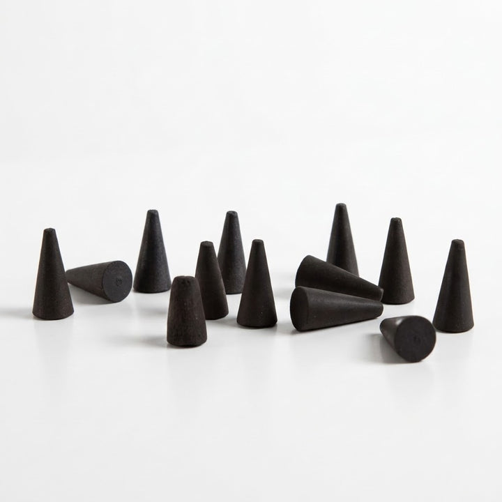 A set of matte black incense cones arranged on a clean white surface.